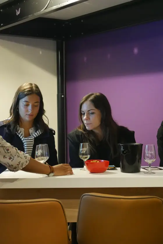Gruppe von Teilnehmern am Tisch bei einem Wine-Break-Abend, violette Wände