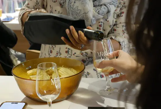 Wein wird in ein Glas mit Le-Petit-Musée-du-Vin-Logo gegossen bei einem Wine-Break-Abend