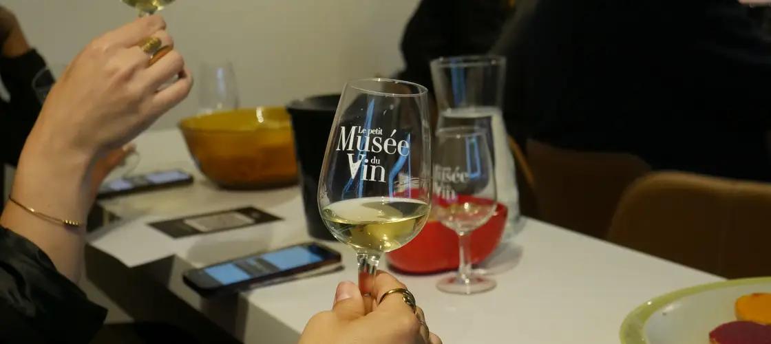Teilnehmer halten Gläser mit Le-Petit-Musée-du-Vin-Logo — warme Wine-Break-Atmosphäre